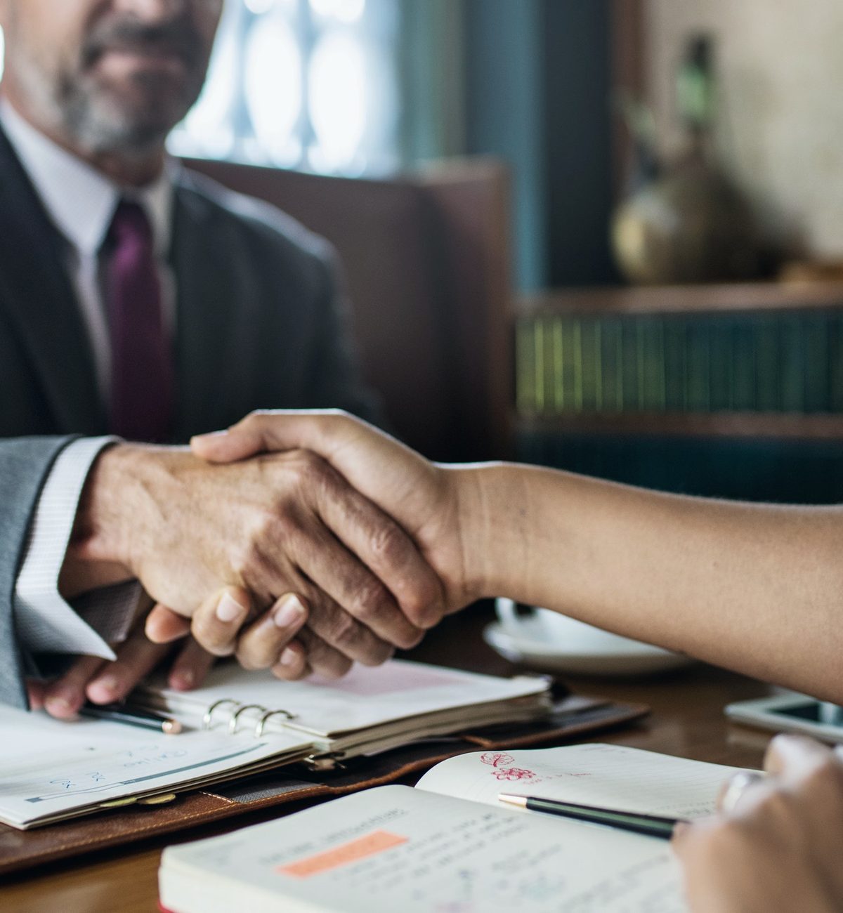 An attorney shaking hands with a client across a desk